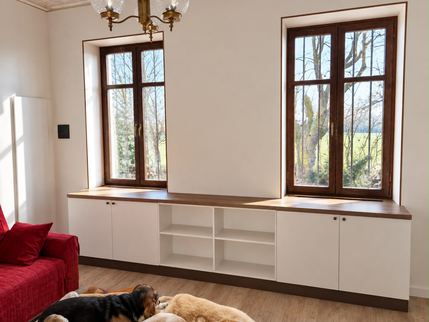 Mobile contenitore bianco su misura con piano in legno, ante e vani a giorno sotto due finestre